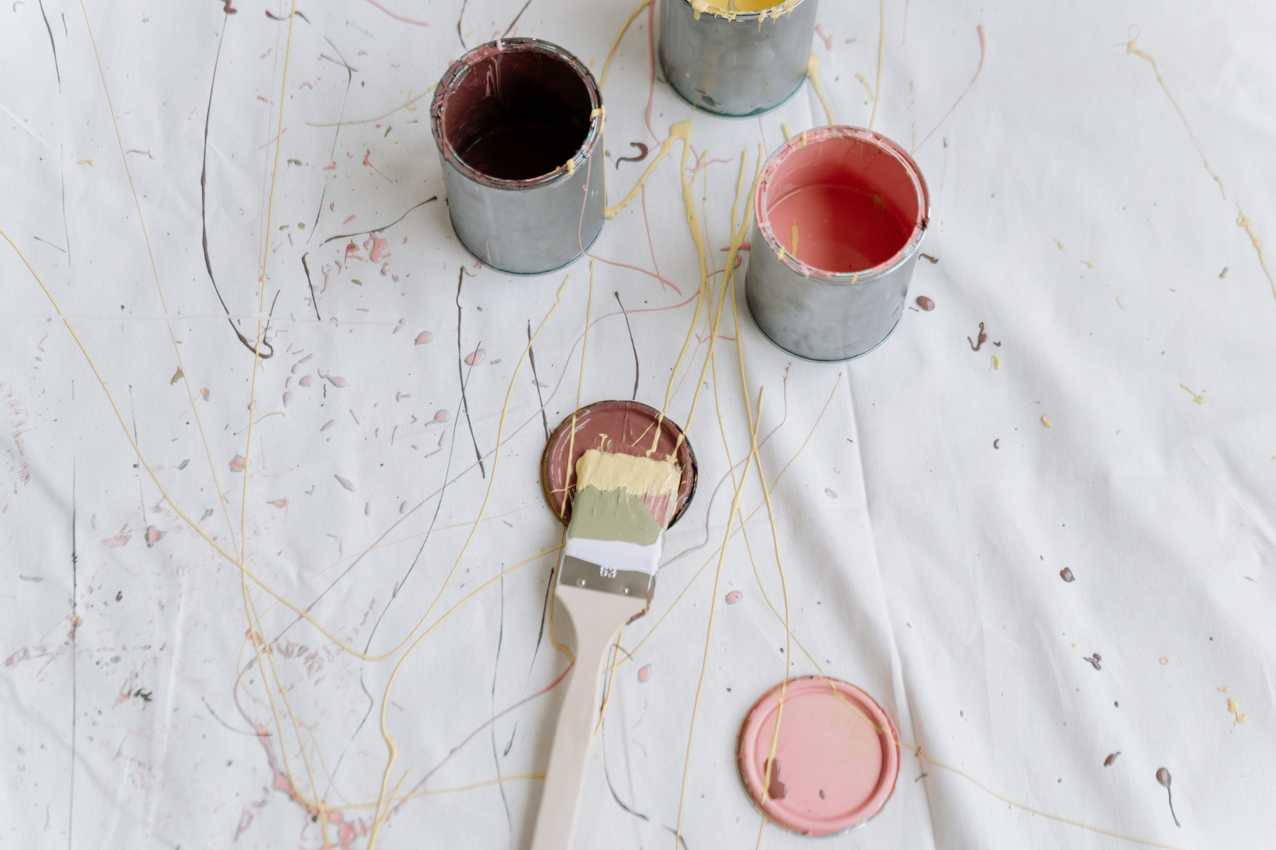 A Paint Splatter on a White Surface Near the Cans